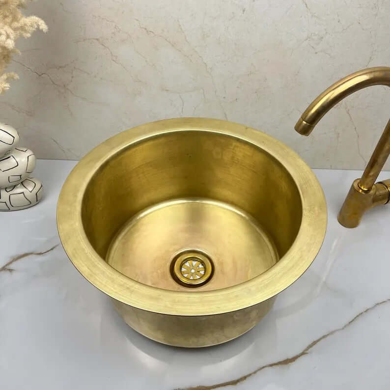 Handcrafted round brass sink showcasing a warm patina, ideal for kitchen or bathroom luxury decor.