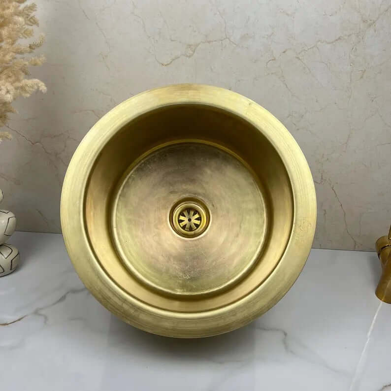Round brass basin sink, handcrafted luxury for kitchen and bathroom, showcasing elegant patina.