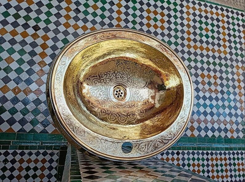 Copper basin with intricate designs, displayed against a colorful tiled background.