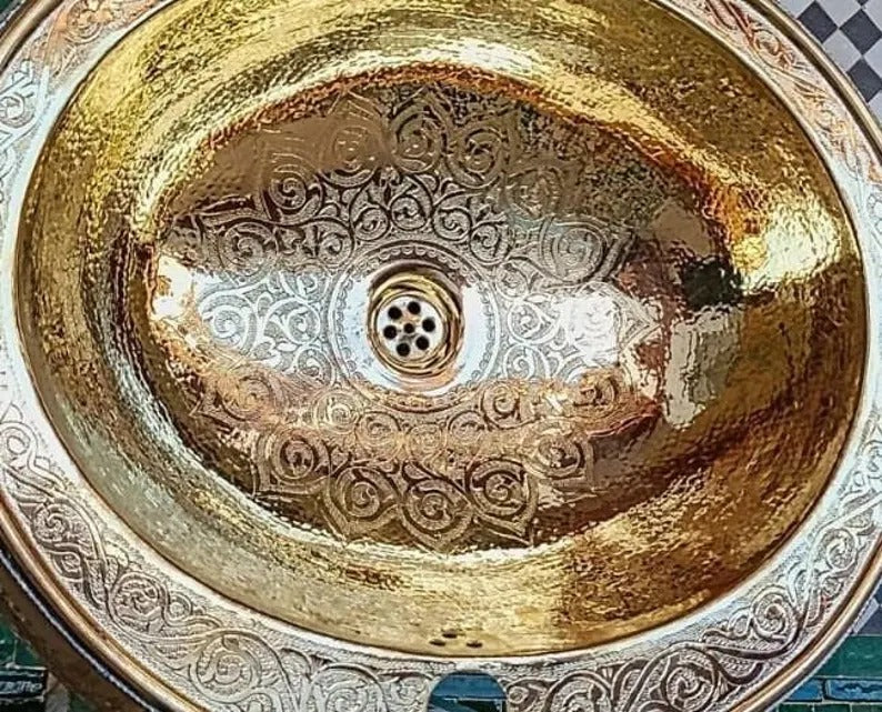 Elegant copper sink with intricate engravings, showcasing a golden finish and artistic design details.