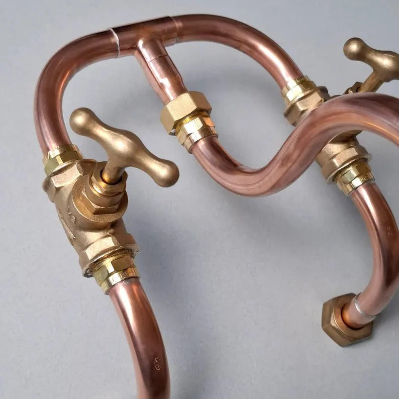 Close-up of handmade copper and brass plumbing faucet components, showcasing industrial design and quality craftsmanship.