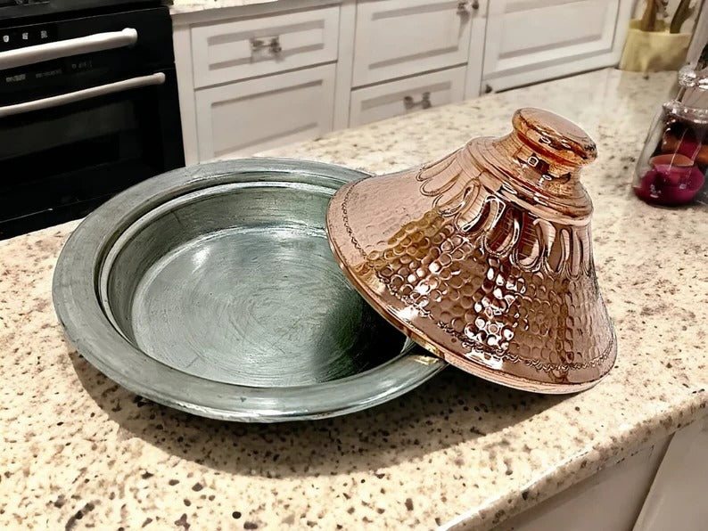 Luxurious handcrafted Moroccan copper tagine with lid on serving tray, showcasing intricate design and craftsmanship.