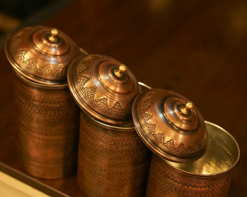 Set of 3 handmade antique copper spice jars with intricate designs and lids, perfect for kitchen decor.