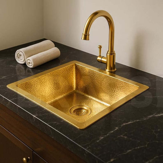 Handcrafted brass bar sink with golden finish and elegant faucet on a marble countertop.