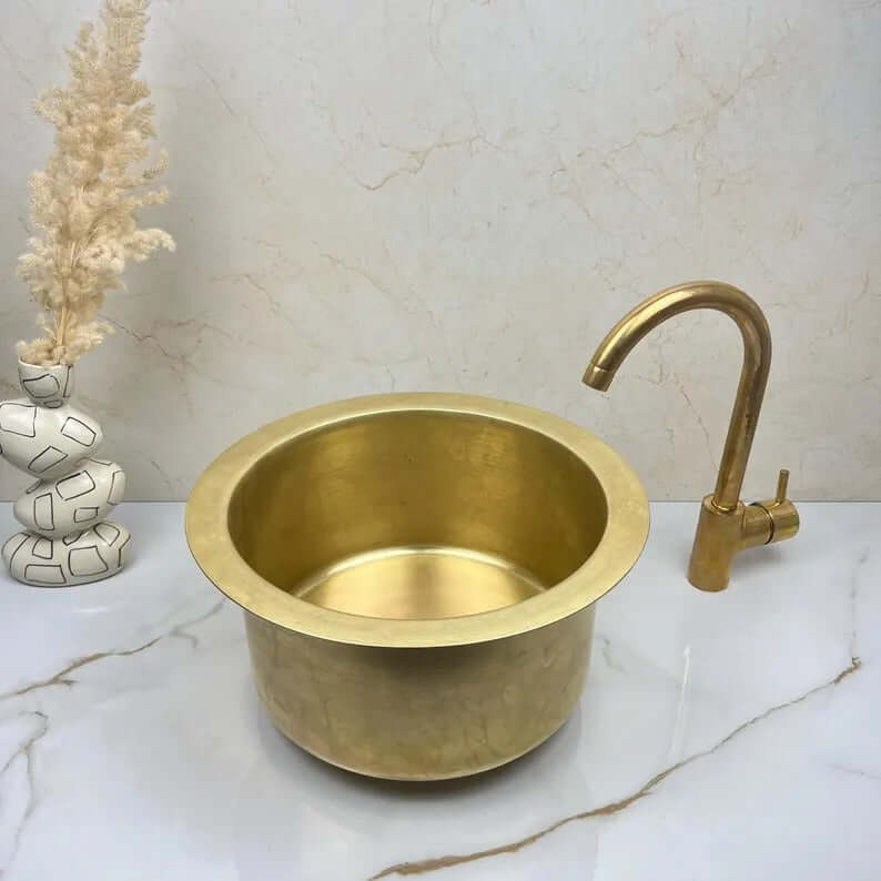 Handcrafted round brass basin sink with elegant faucet, showcasing a luxury design for kitchens and bathrooms.