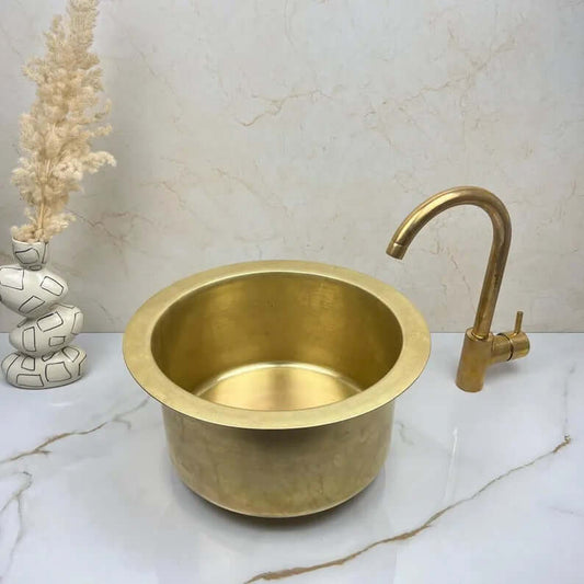 Handcrafted round brass basin sink with elegant faucet, showcasing a luxury design for kitchens and bathrooms.