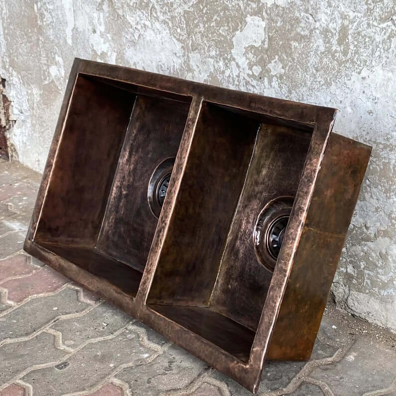 Handmade double vessel sink in copper, showcasing two basins for kitchen or bathroom decor.