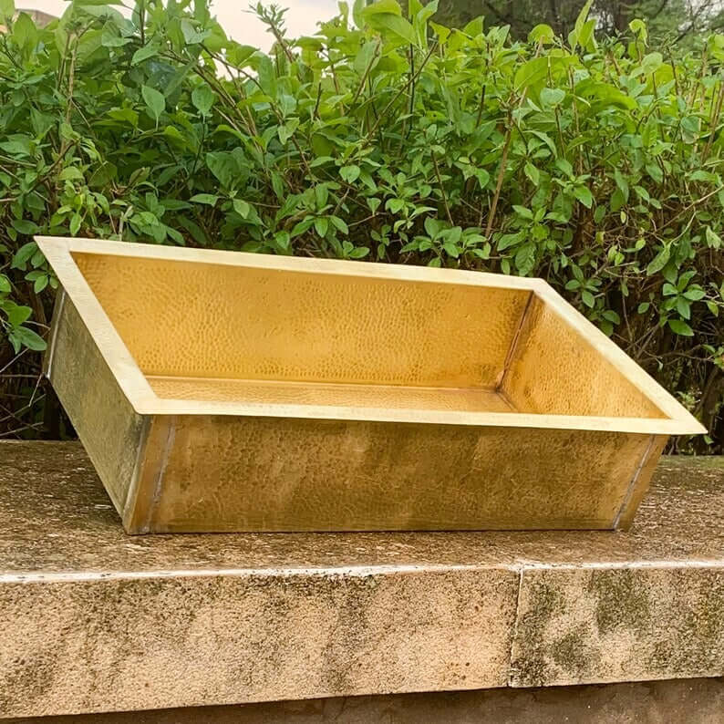 Handmade golden brass sink resting on a stone surface, designed for bathrooms, showcasing Moroccan craftsmanship.