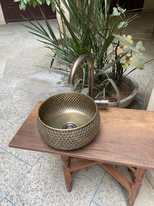 Hand hammered brass kitchen sink with intricate design, showcasing Moroccan craftsmanship on a wooden table.