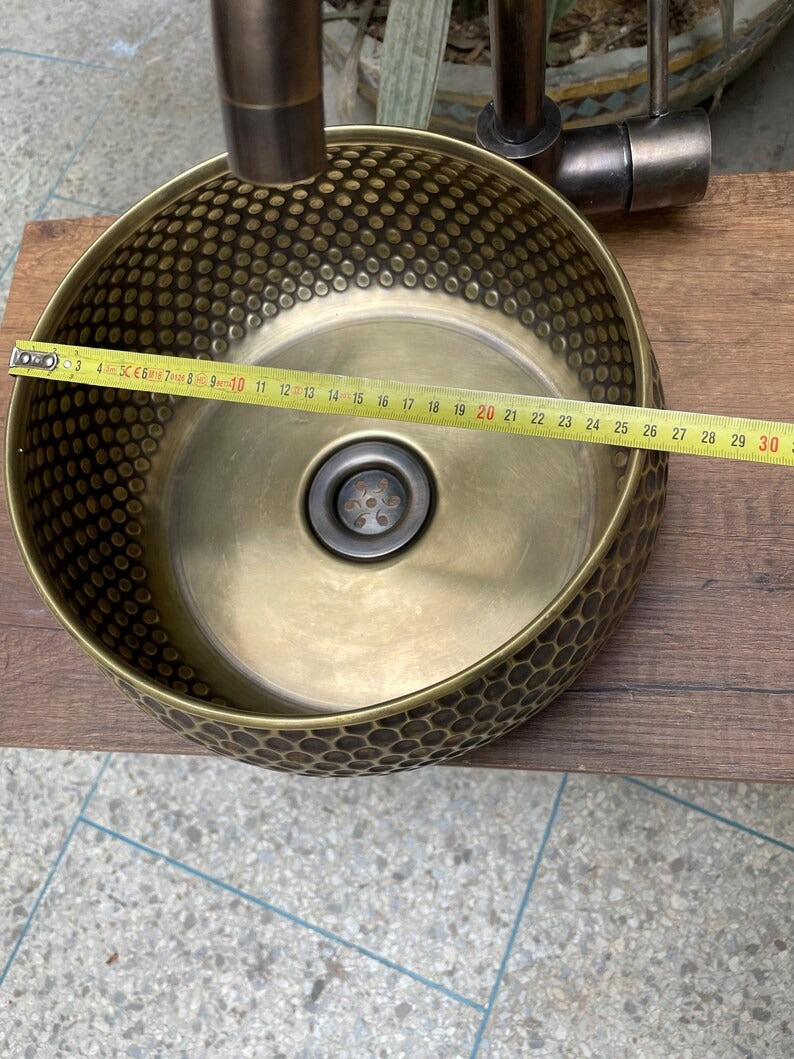 Hand hammered brass kitchen sink showcasing handmade Moroccan design with measuring tape for scale.