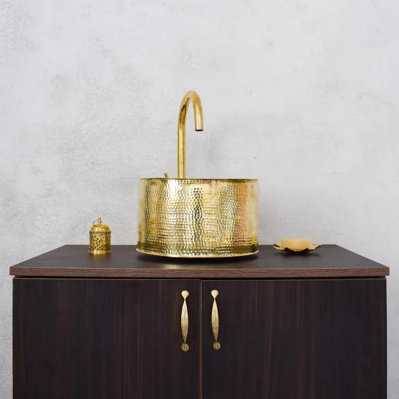 Handmade brass sink with a stylish faucet on a wooden cabinet, showcasing traditional Moroccan craftsmanship.