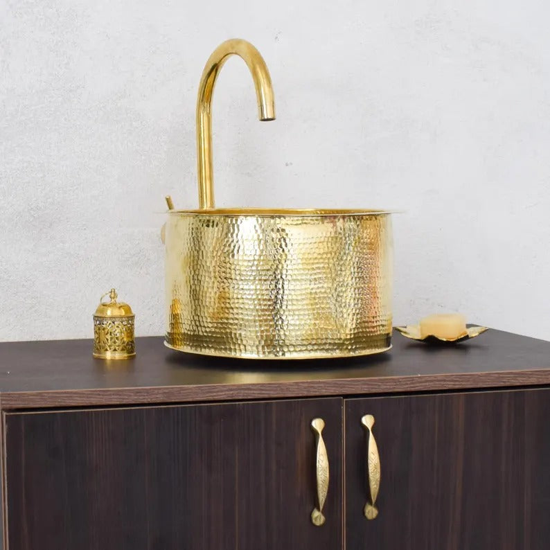 Handmade brass sink with hammered finish, styled with decorative accessories in a modern bathroom setting.