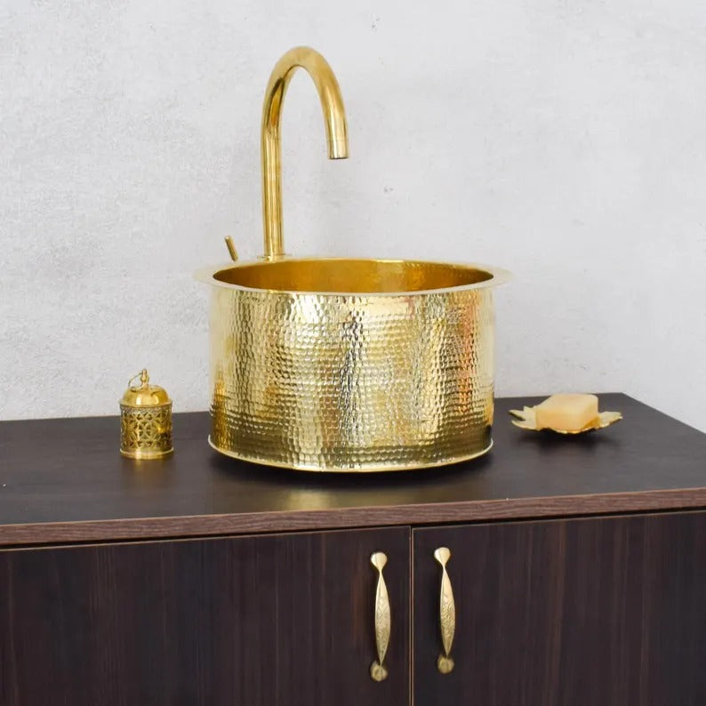 Handmade brass sink with elegant faucet on a wooden counter, featuring a traditional Moroccan design.