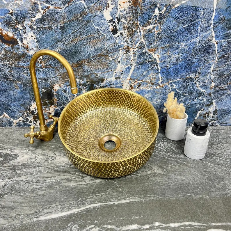 Hand-hammered brass round sink with drain, showcasing Moroccan craftsmanship and elegance in a modern bathroom setting.
