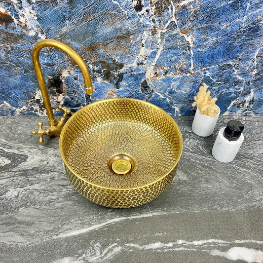 Hand-hammered brass round sink with drain, showcasing elegant texture and Moroccan craftsmanship, ideal for luxury bathrooms.