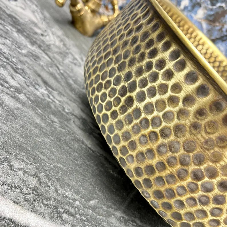 Close-up of a hand-hammered brass round sink showcasing its unique textured surface and elegant design.