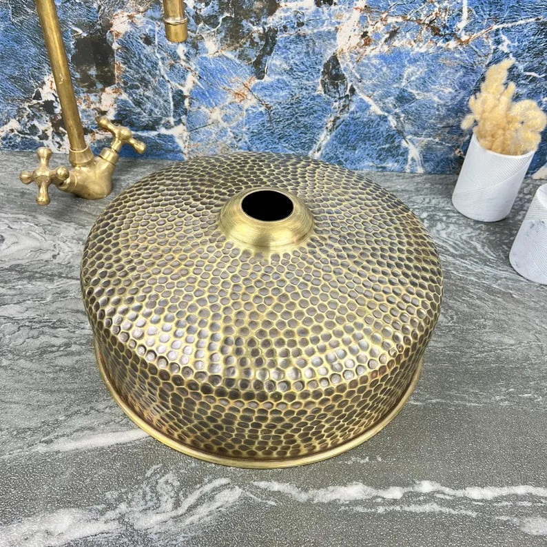Handmade hammered brass round sink with drain, showcasing traditional Moroccan craftsmanship.