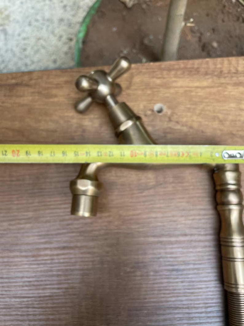 Brass water filter faucet with a single handle, measuring tape on wooden surface for installation reference.