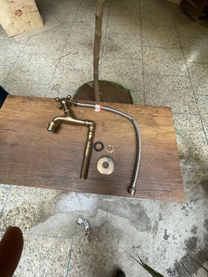 Brass water filter faucet parts on a wooden table, showcasing the faucet, hose, and installation components.
