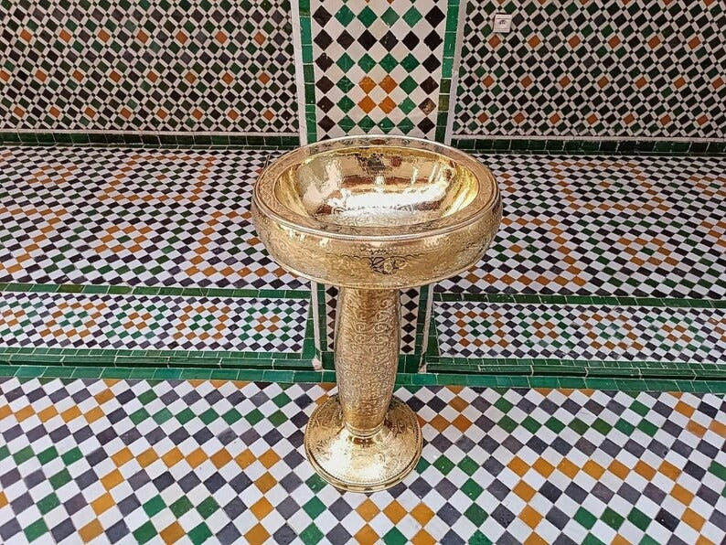 Elegant copper basin on a patterned tiled floor, showcasing intricate design and craftsmanship.