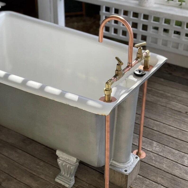 Handmade copper and brass faucet on vintage bathtub, showcasing rustic farmhouse design.