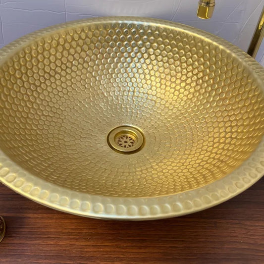 Handmade brass sink with a hammered finish, showcasing elegant texture perfect for bathroom or kitchen decor.