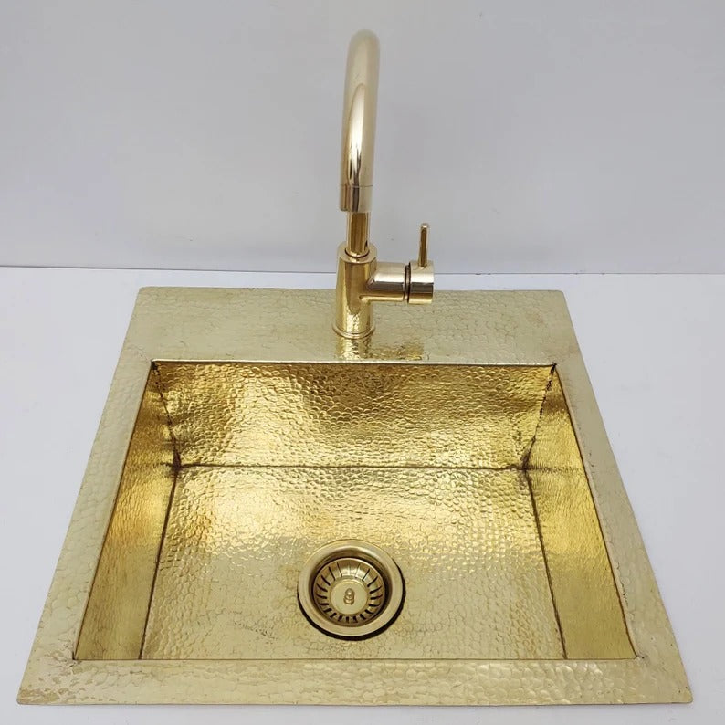 Unlacquered hammered solid brass sink with matching faucet, ideal for rustic or farmhouse kitchen styles.