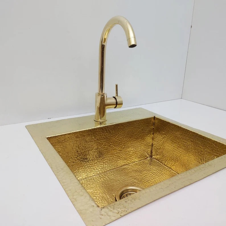 Unlacquered hammered solid brass sink with matching faucet, ideal for rustic or farmhouse kitchens.