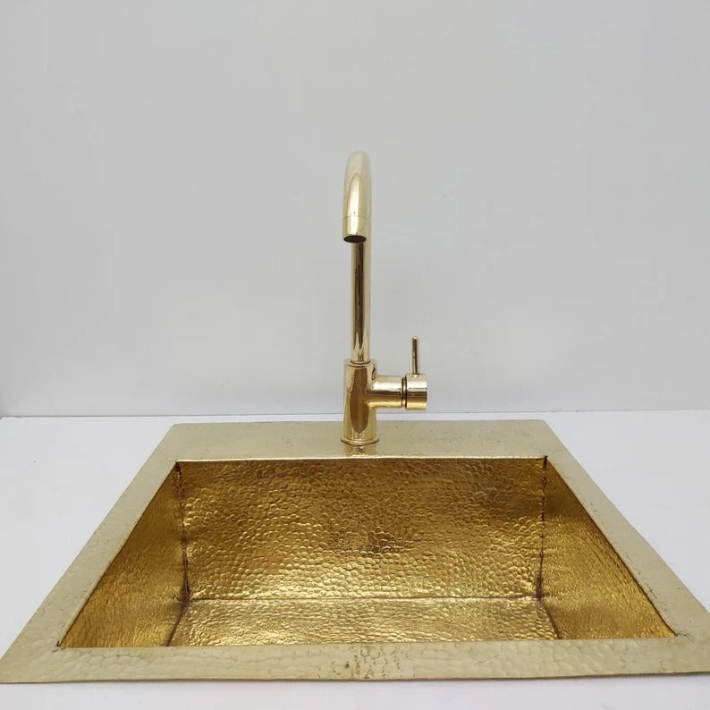 Unlacquered hammered solid brass sink with matching faucet, perfect for rustic or farmhouse kitchens, showcasing luxury and durability.