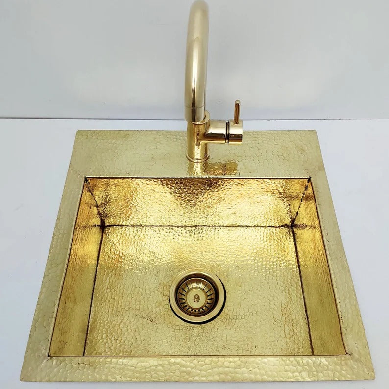 Unlacquered hammered brass sink with matching faucet, showcasing elegant hammered texture.
