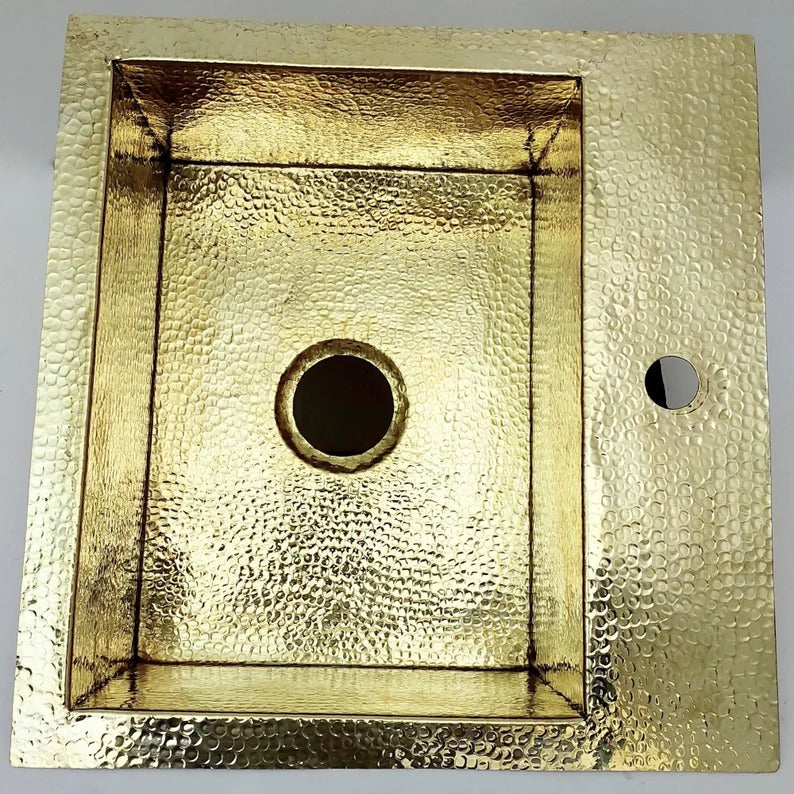 Unlacquered hammered solid brass sink with a round drain hole, ideal for rustic or farmhouse kitchens.