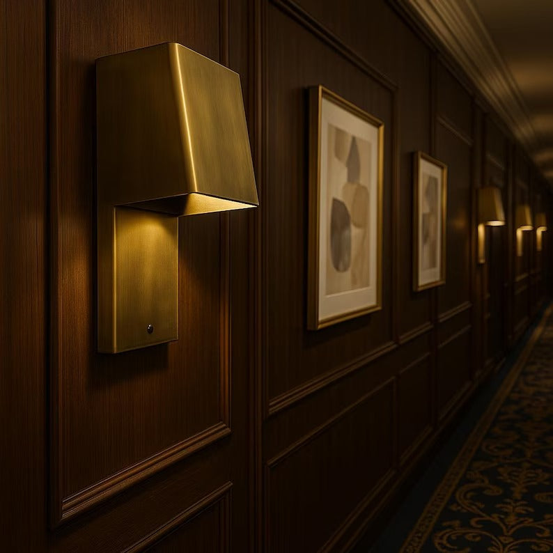 Handcrafted brass wall sconce illuminating a luxurious hallway with artwork.