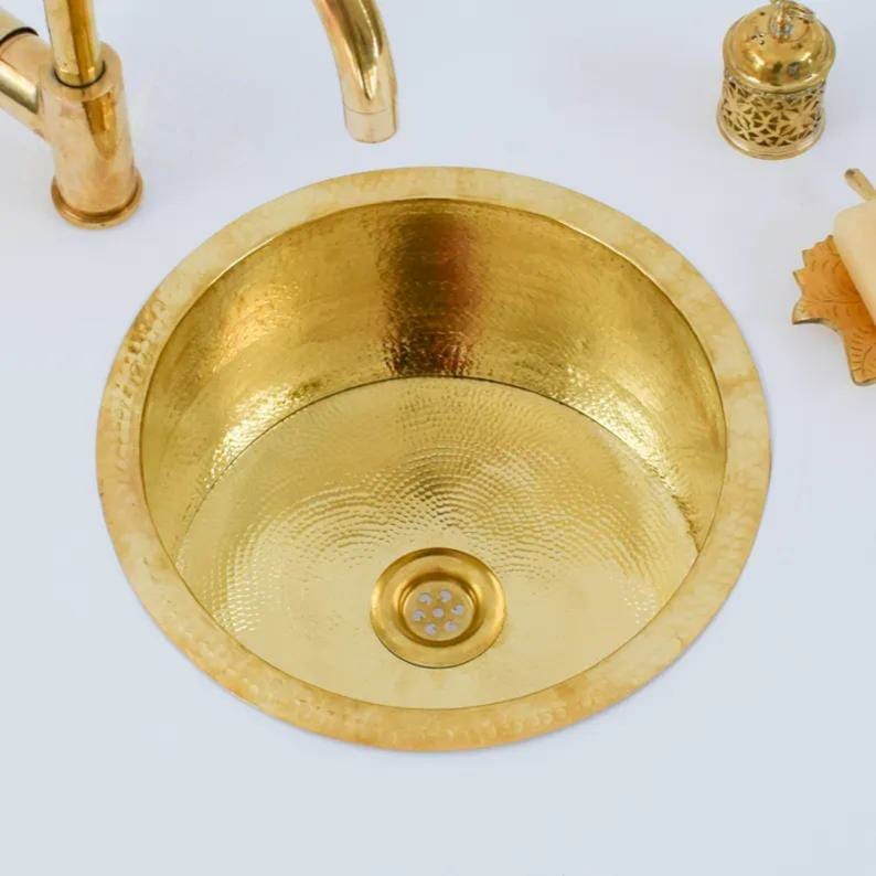 Handmade brass sink featuring a hammered finish, perfect for a bathroom with traditional Moroccan design.