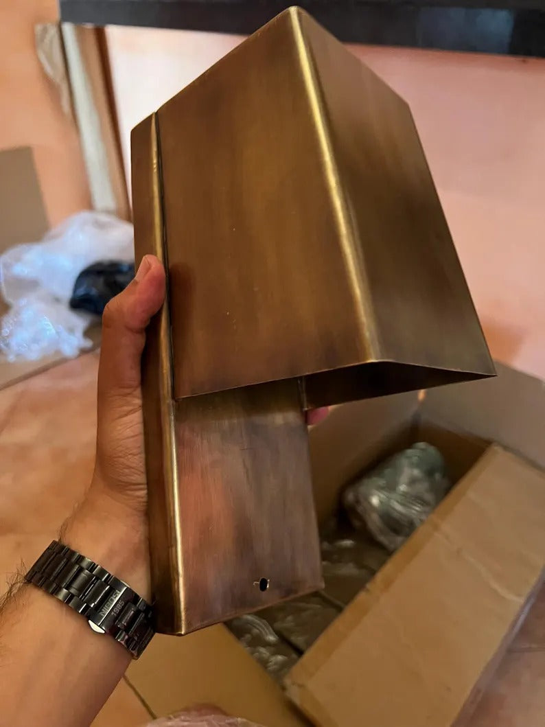 Handcrafted copper wall sconce held in hand, showcasing modern minimalist design and rich copper finish.